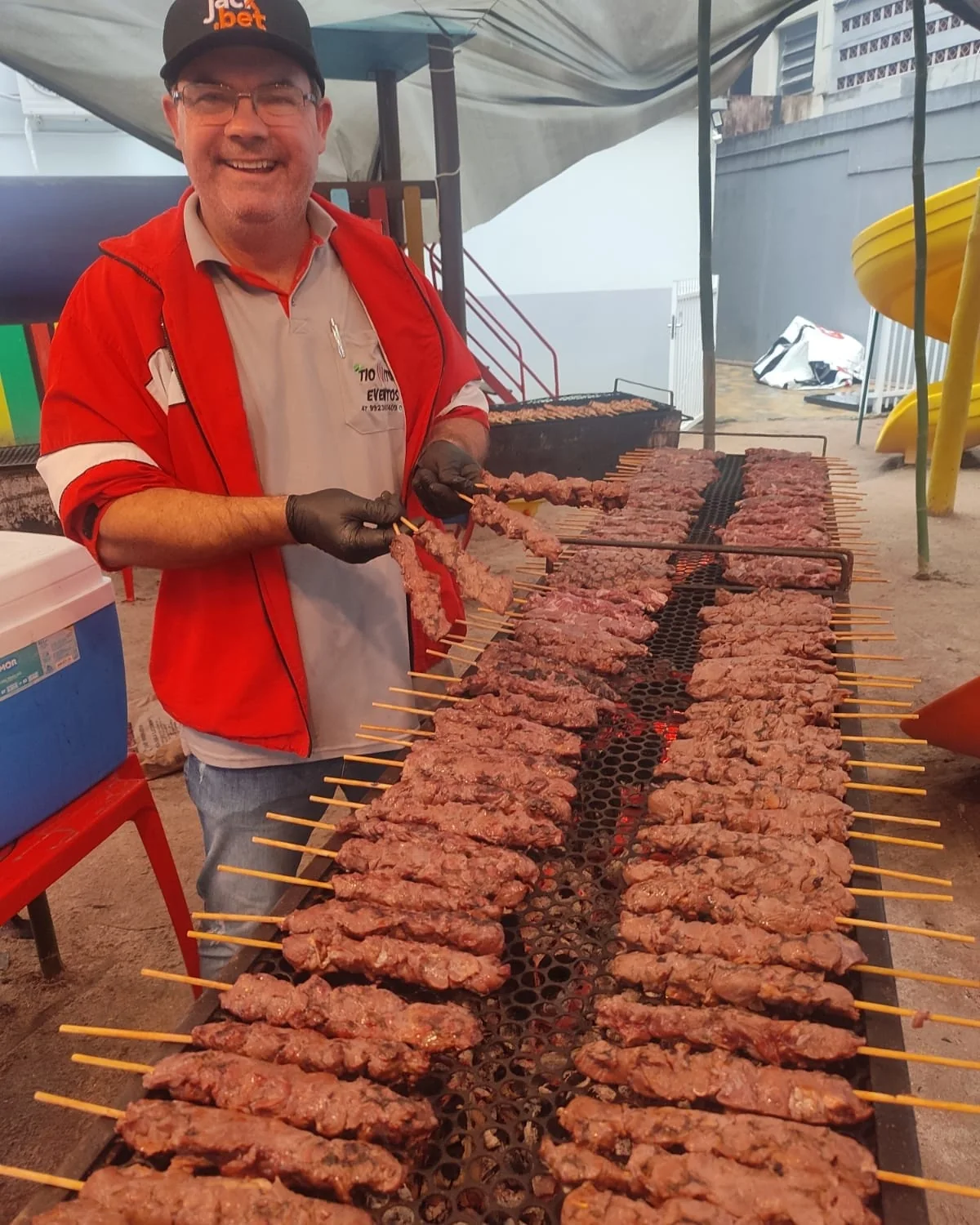 Atendimento com um sorriso ao lado da churrasqueira cheia de espetinhos